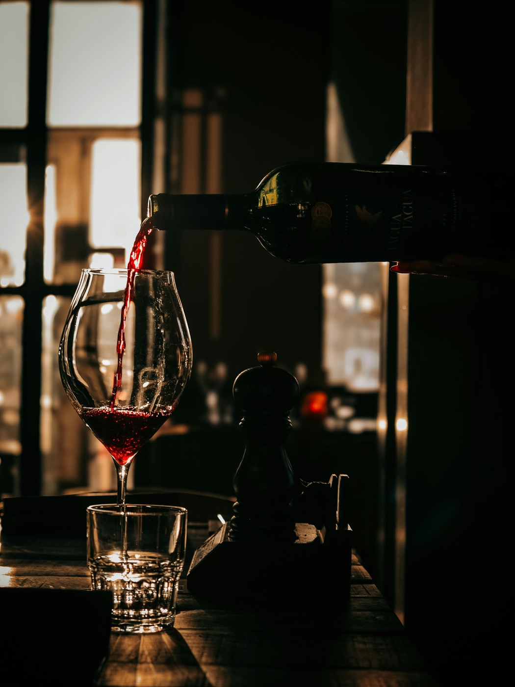 Red wine being poured into a glass in dramatic low light