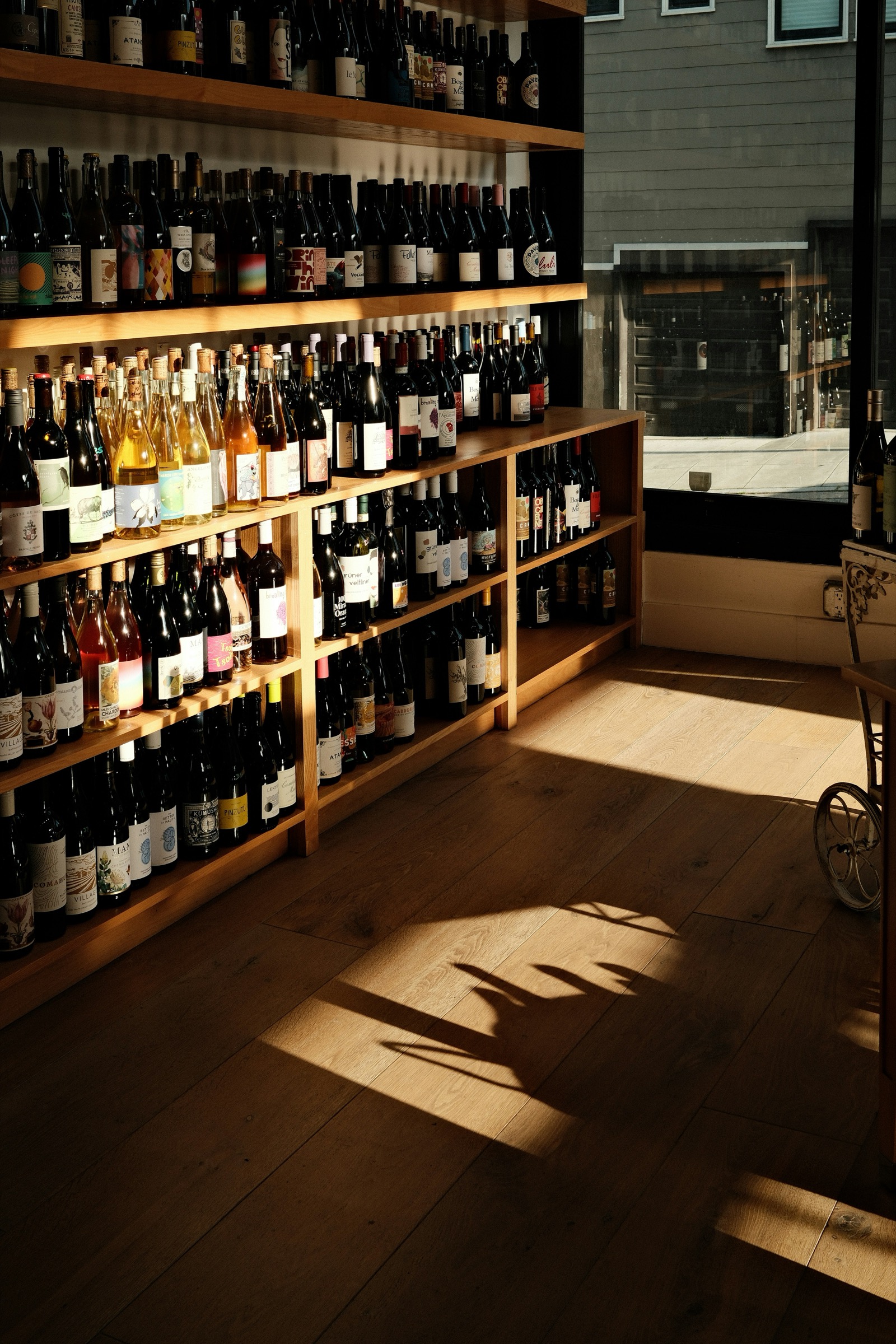 Independent wine shop interior at evening, warm light falling across shelves of bottles